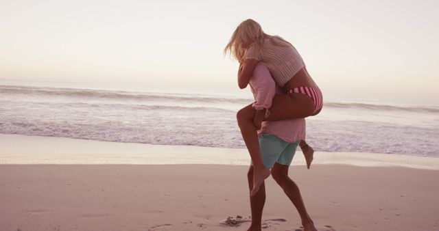 Happy diverse couple playing piggy back on beach. Lifestyle, relaxation, nature, free time and vacation.