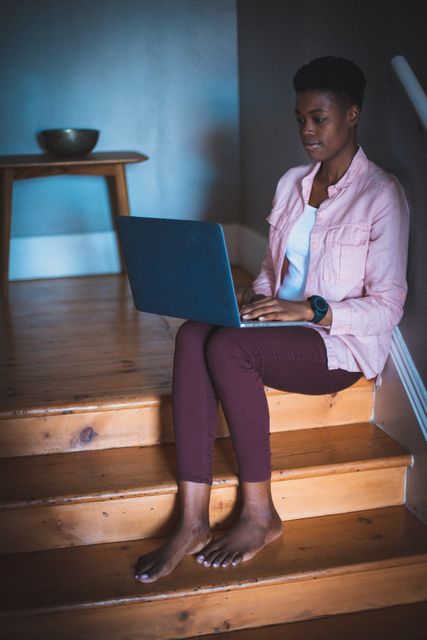 African american woman working at home sitting on stairs using laptop - Download Free Stock Photos Pikwizard.com
