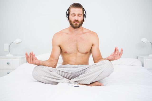 Man doing yoga while listening to music on bed - Download Free Stock Photos Pikwizard.com