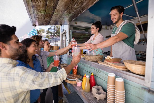 Smiling waitress and waiter giving juice to customer at counter