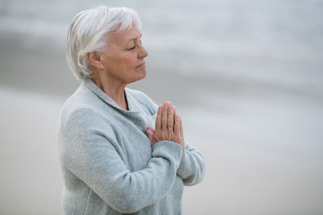 Senior woman praying on the beach - Download Free Stock Photos Pikwizard.com