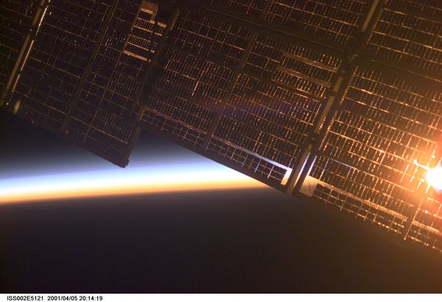 ISS002-E-5121 (5 April 2001) --- The solar panel supporting the Zvezda Service Module on the International Space Station (ISS)  is backdropped against Earth's horizon at dawn. The image was made by one of the Expedition Two crew members using a digital still camera.