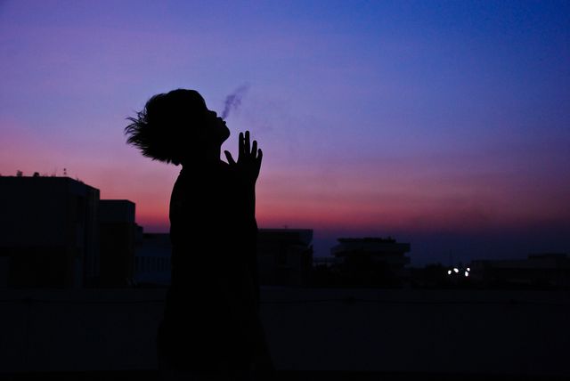 silhouette of man smoke cigarette on top of building- Download Free Stock Photos Pikwizard.com