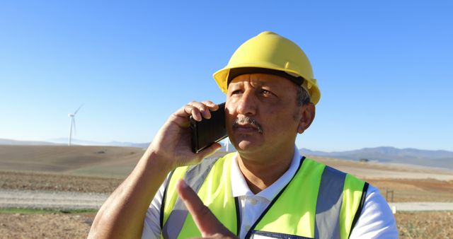 A man in construction attire discusses a serious renewable energy matter on his phone. - Download Free Stock Photos Pikwizard.com