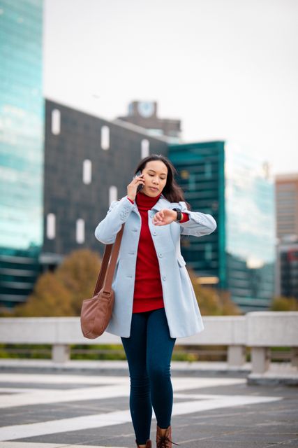Asian woman crossing road, talking by smartphone and checking smartwatch - Download Free Stock Photos Pikwizard.com