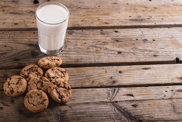High angle view of cookies by glass of milk on wooden table with copy space - Download Free Stock Photos Pikwizard.com
