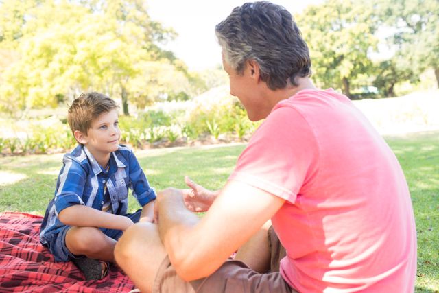 Father talking to son at picnic in park - Download Free Stock Photos Pikwizard.com