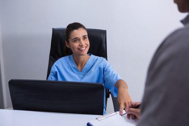 Smiling doctor interacting with patient at desk - Download Free Stock Photos Pikwizard.com