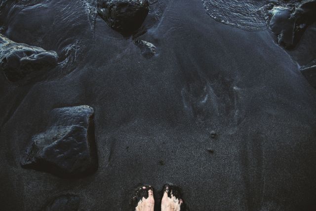 a person's feet on the black sand - Download Free Stock Photos Pikwizard.com