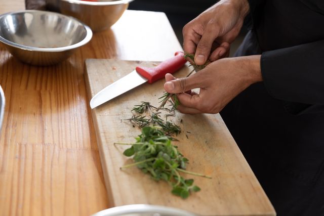 Caucasian male chef cutting herbs on a chopping board - Download Free Stock Photos Pikwizard.com