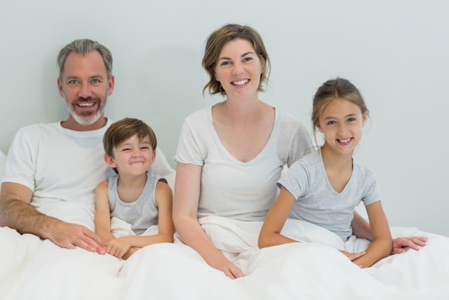 Happy family sitting together on bed in bedroom at home - Download Free Stock Photos Pikwizard.com