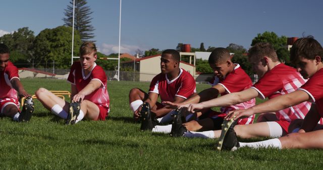 Team of diverse boy rugby players stretching on rugby field with copy ...