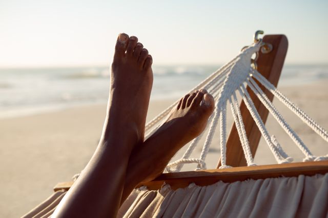 Woman relaxing with feet up in a hammock on the beach - Download Free Stock Photos Pikwizard.com