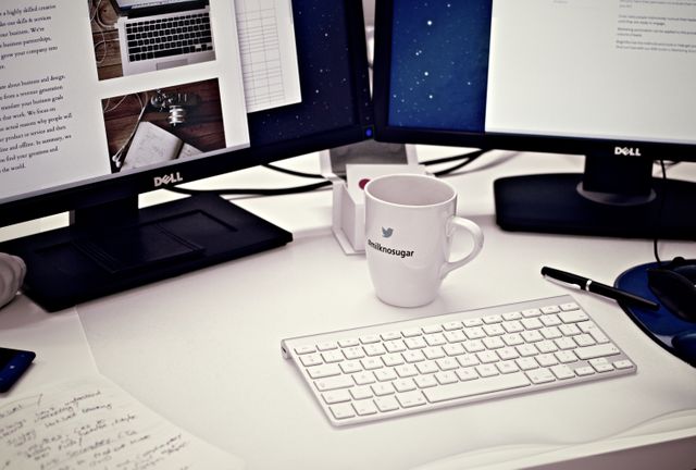 Close up view of two desktop computer and coffee cup on office table. office, business and technology concept