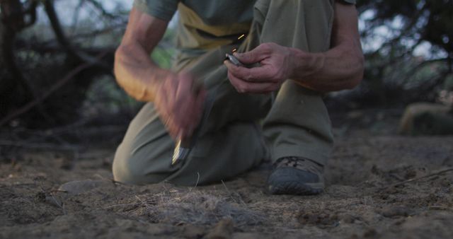 Caucasian male survivalist using knife and flint to spark fire with tinder at camp in wilderness. exploration, travel and adventure, survivalist in nature.