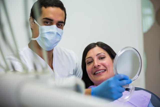 Dentist holding mirror in front of patient - Download Free Stock Photos Pikwizard.com