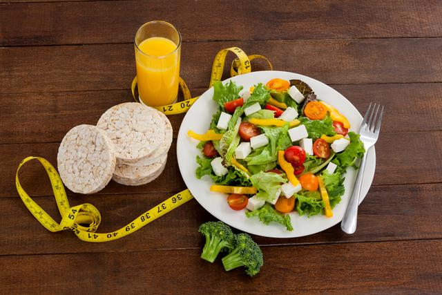 Salad, juice, edible bars and measuring tape on table - Download Free Stock Photos Pikwizard.com