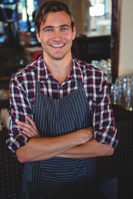 Smiling waiter with arms crossed in a restaurant