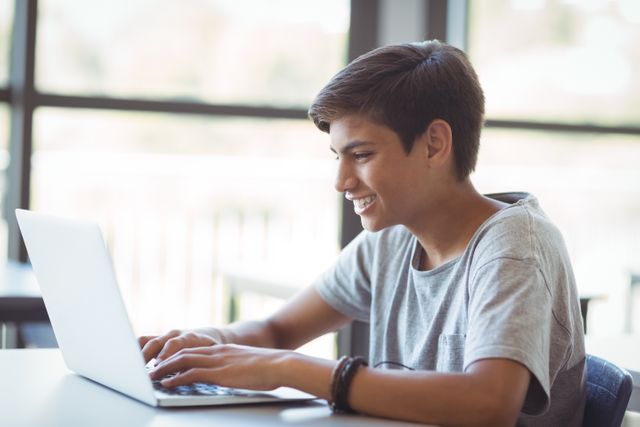 Happy schoolboy using laptop in classroom - Download Free Stock Photos Pikwizard.com