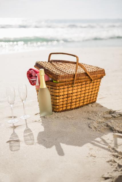 Picnic basket, champagne bottle and two glasses on sand - Download Free Stock Photos Pikwizard.com