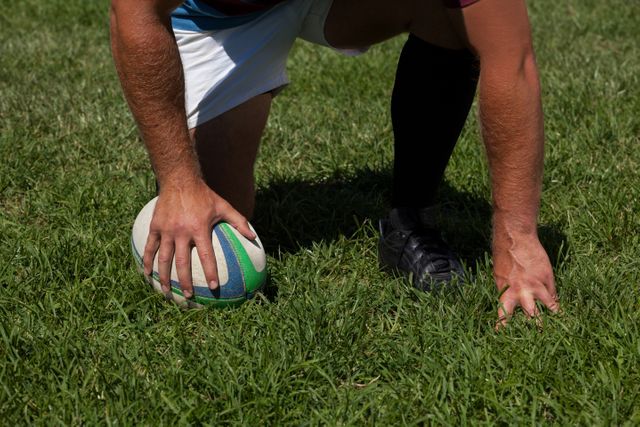 Player crouching with rugby ball on field - Download Free Stock Photos Pikwizard.com
