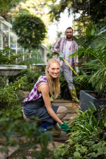Portrait of happy young female gardener with colleague in community garden