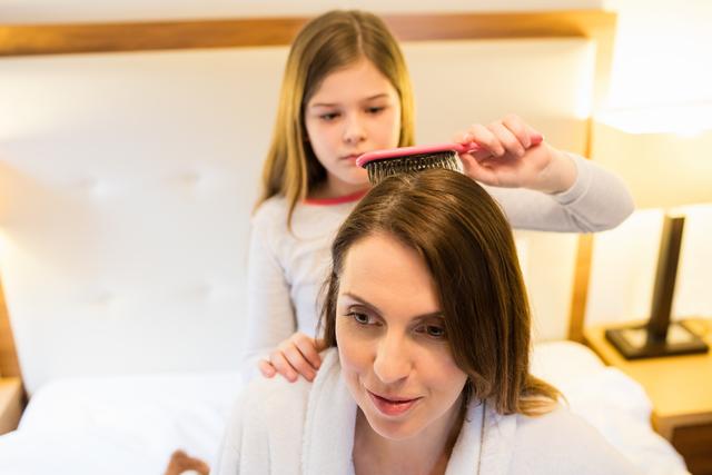Daughter combing her mothers hair in bedroom - Download Free Stock Photos Pikwizard.com