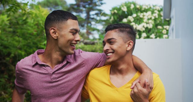 Smiling mixed race gay male couple walking in garden hugging and kissing - Download Free Stock Photos Pikwizard.com