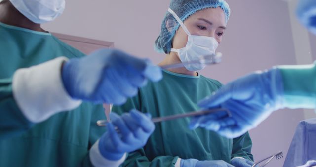 Image of asian female surgeon at work during operation in theatre and colleagues passing instruments. Hospital, medical and healthcare services.