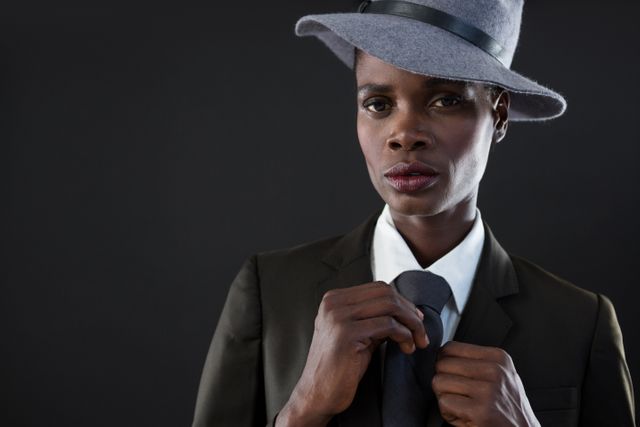 Androgynous man adjusting his tie against grey background