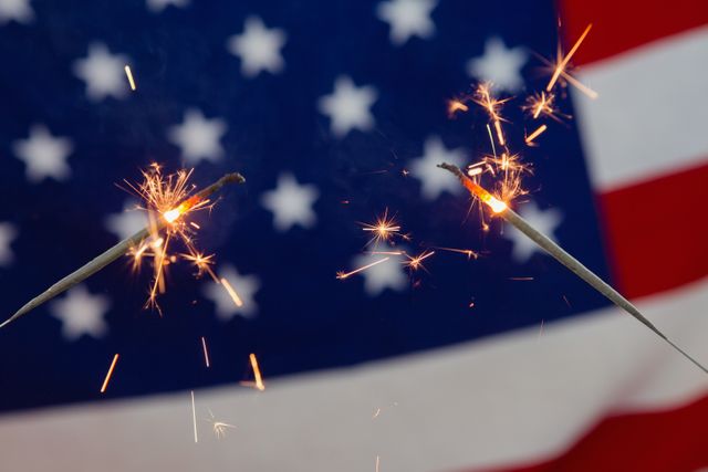 Close-up of sparklers burning against American flag background
