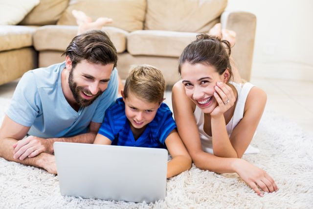 Parents and son lying on rug and using laptop - Download Free Stock Photos Pikwizard.com