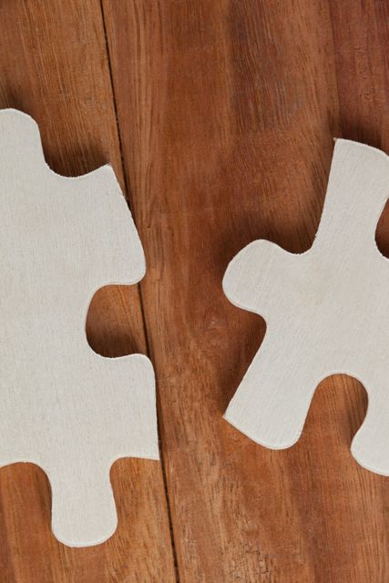 Two piece of jigsaw puzzle on wooden background