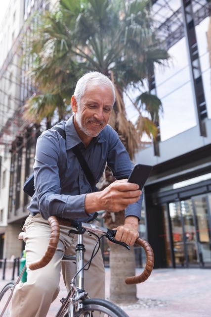 Senior man on bicycle using smartphone - Download Free Stock Photos Pikwizard.com