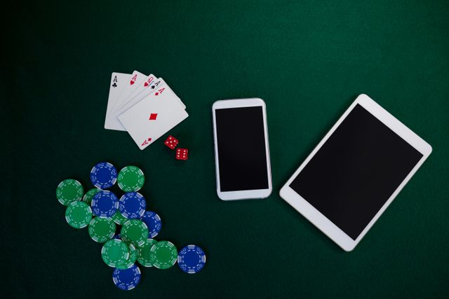 Electronic gadgets, playing cards, mobile phone, dice and casino chips on poker table in casino