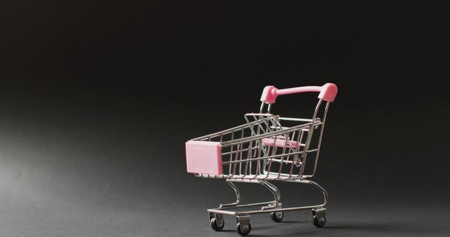 Empty shopping trolley on seamless, lit black background with copy space. Black friday, shopping, sale and retail concept digitally generated image.