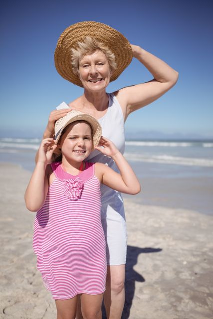 Portrait of girl with grandmother wearing sun hat at beach - Download Free Stock Photos Pikwizard.com