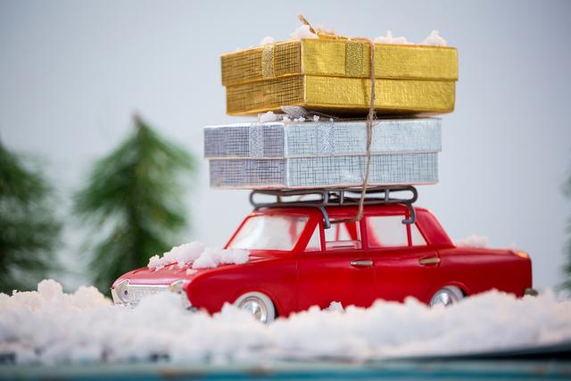 Toy car carrying christmas present on fake snow during christmas time