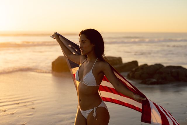 Young woman in bikini holding an American flag on the beach