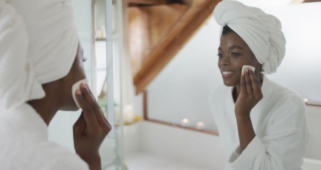 Portrait of african american attractive woman removing make up in bathroom. beauty, pampering, home spa and wellbeing concept.