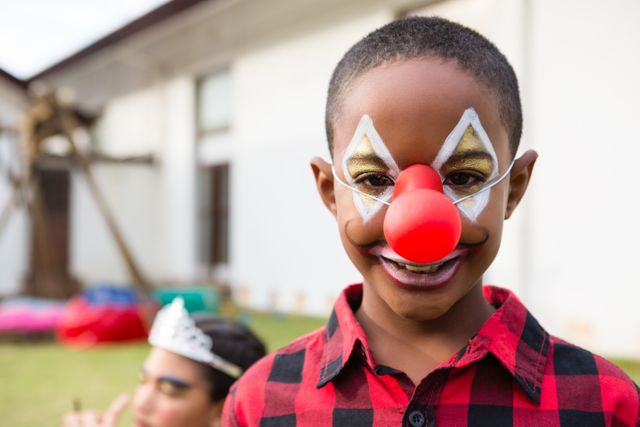 Portrait of boy with face paint wearing clown nose - Download Free Stock Photos Pikwizard.com