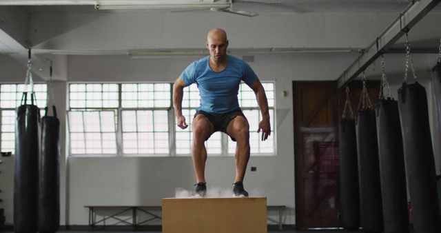 Fit caucasian man jumping on pylo box at the gym. sports, training and fitness concept