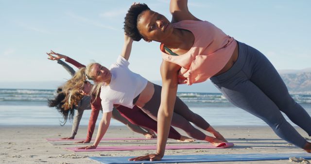 Group of diverse female friends practicing yoga at the beach. healthy active lifestyle, outdoor fitness and wellbeing.