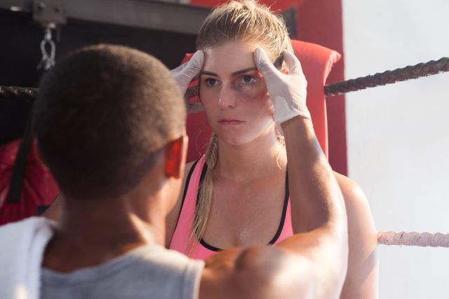 Trainer giving head massage to woman in boxing ring