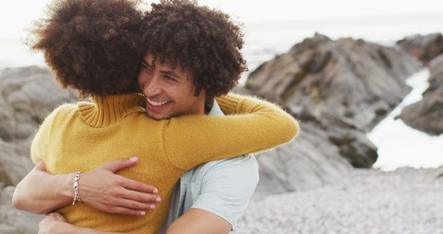 African american couple hugging each other sitting on the rocks near the sea - Download Free Stock Photos Pikwizard.com