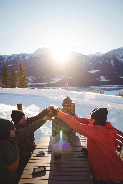 Skiers friends toasting glasses of beer in ski resort during winter