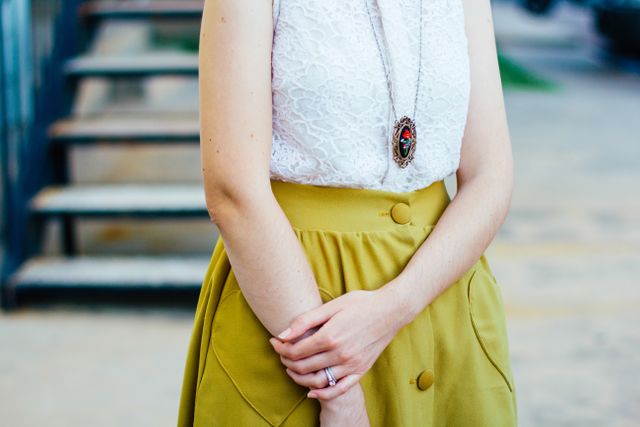 Mid section of woman wearing a white top and yellow skirt. fashion and style concept