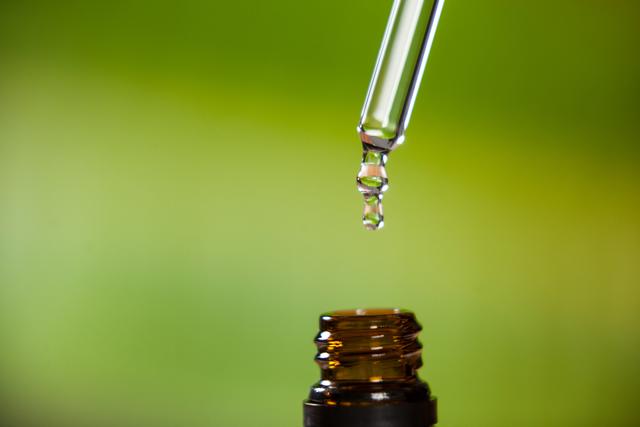 Drop of oil dripping from pipette into bottle of essential oil - Download Free Stock Photos Pikwizard.com