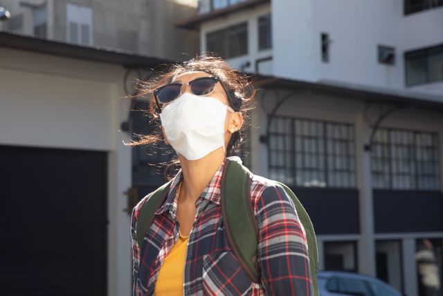 Young woman wearing face mask outdoors on a sunny day - Download Free Stock Photos Pikwizard.com