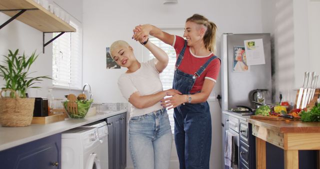 Happy diverse female couple embracing and dancing together in kitchen - Download Free Stock Photos Pikwizard.com